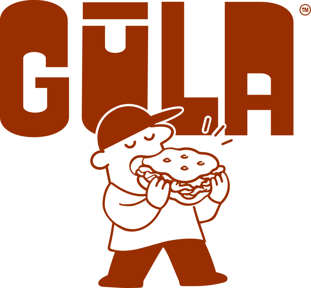 GŪLA — la mascotte croque dans un sandwich